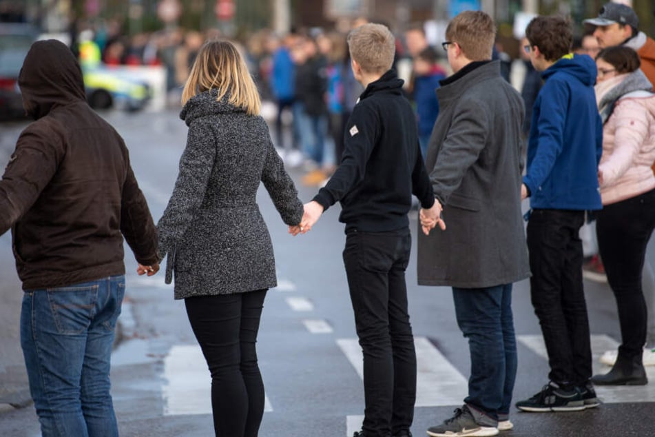 Schüler stehen während der Gedenkfeier in einer Menschenkette.