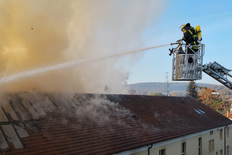 Ein Feuerwehrmann hält einen Wasserschlauch auf das brennende Haus.