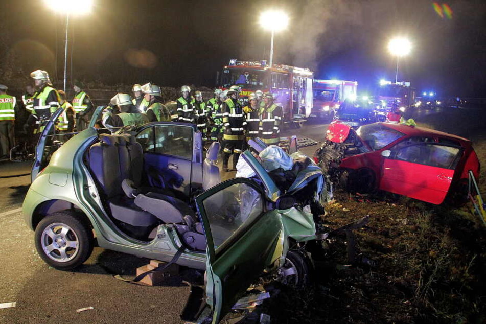 Rettungskräfte und zwei zerstörte Fahrzeuge stehen an einer Unfallstelle. Zwei junge Frauen starben bei dem Unfall, zwei weitere Frauen wurden schwer verletzt. (Archivbild)