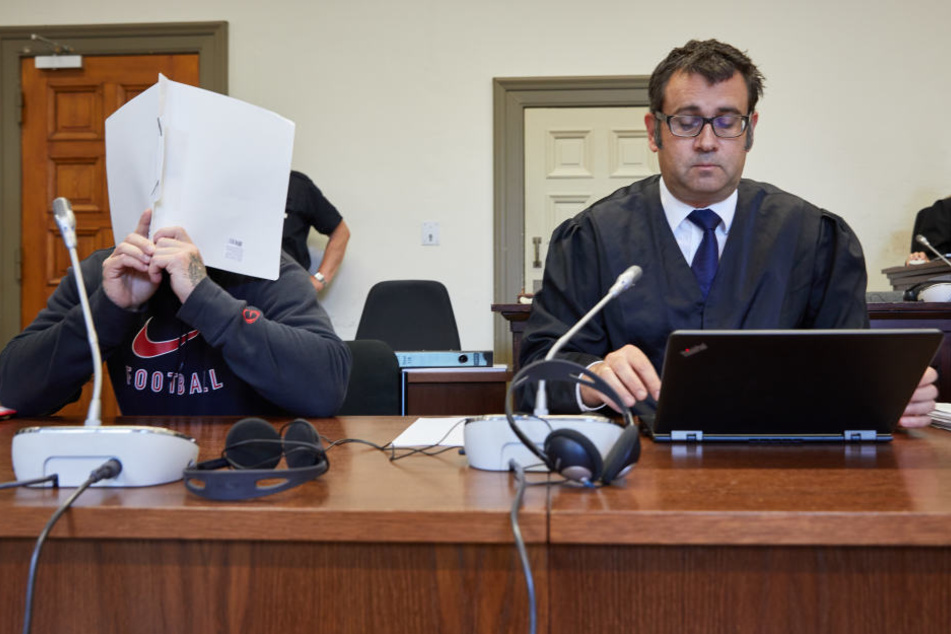 Der Angeklagte (links) und sein Anwalt sitzen in einem Sitzungssaal des Strafjustizgebäudes.