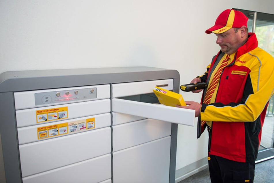 Paketzusteller Marko Zimmermann steht vor einem Paketkasten für Mehrfamilienhäuser in einer Wohnanlage in Berlin.