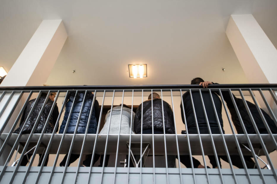 Zuhörer warten auf einer Bank vor dem Gerichtssaal des Wuppertaler Landgerichts.