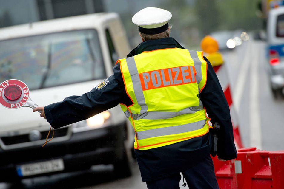 Ein Polizist kontrolliert an der bayerischen Grenze zu Österreich einreisende Autos.