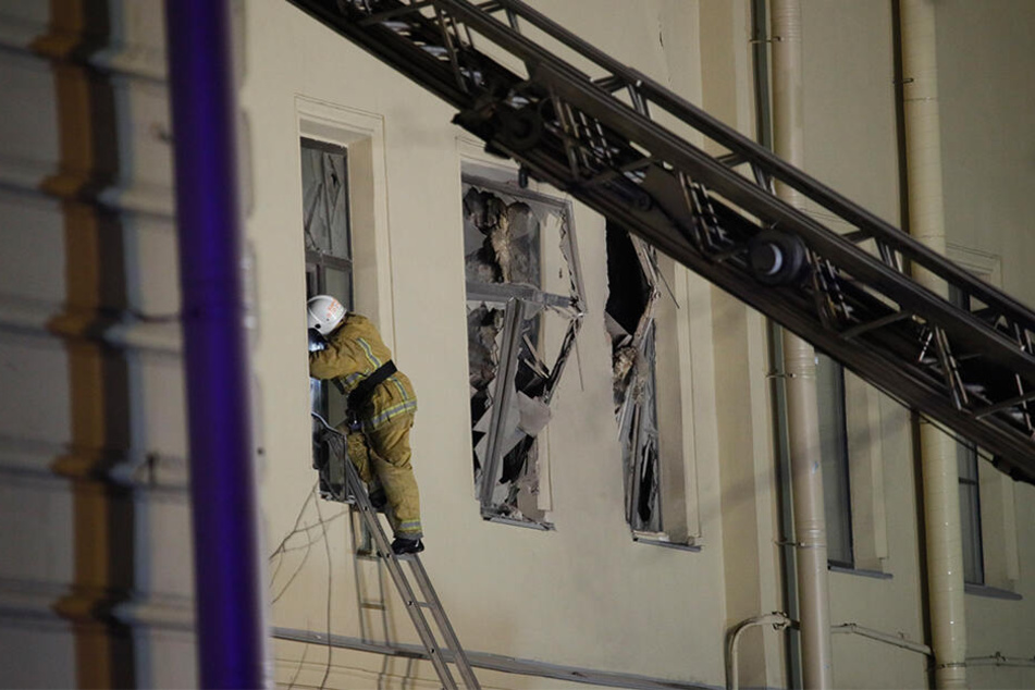 Ein Feuerwehrmann steigt durch ein Fenster eines Universitätsgebäude.