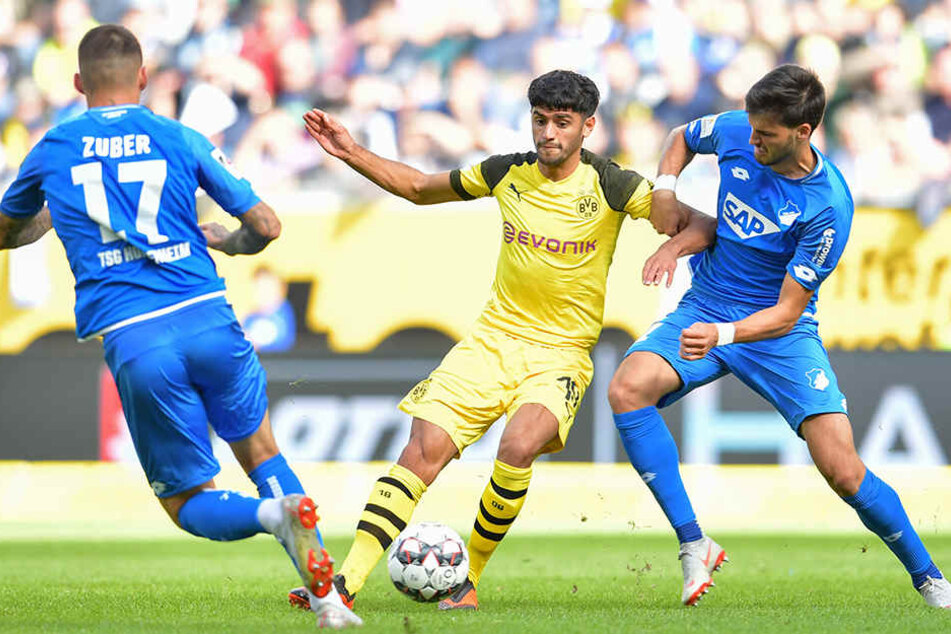 Dortmunds Mahmoud Dahoud (M.) im Zweikampf mit Hoffenheims Florian Grillitsch (r.), der Unterstützung von seinem Teamkollegen Steven Zuber (l.) bekommt.