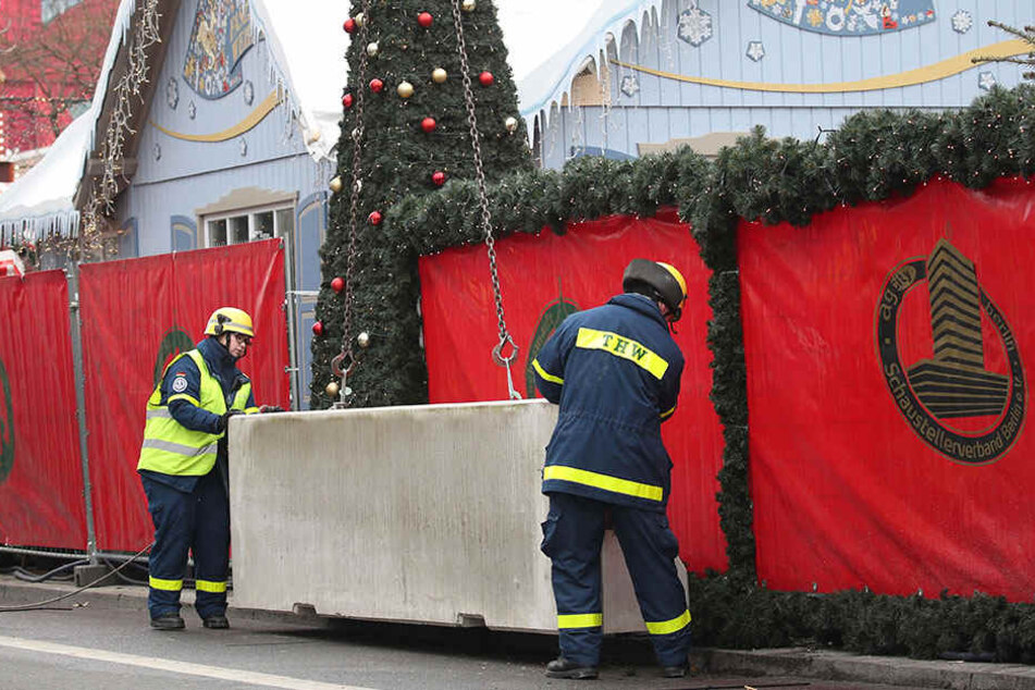 Feuerwehrmänner platzieren den Betonpoller vor dem Weihnachtsmarkt am Breitscheidplatz.