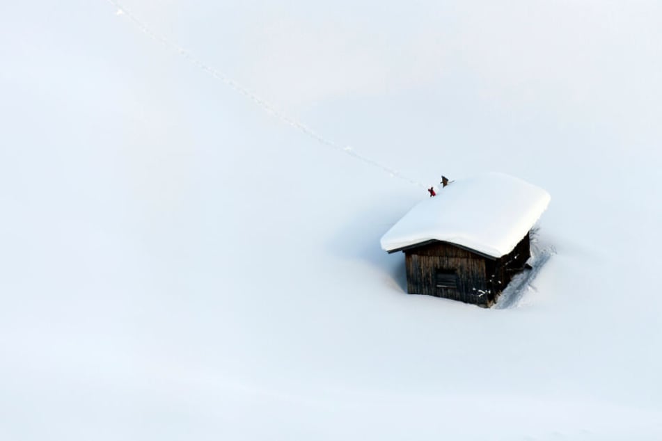 Ein Haus in Österreich in den Schneemassen: Menschen räumen das Dach frei.