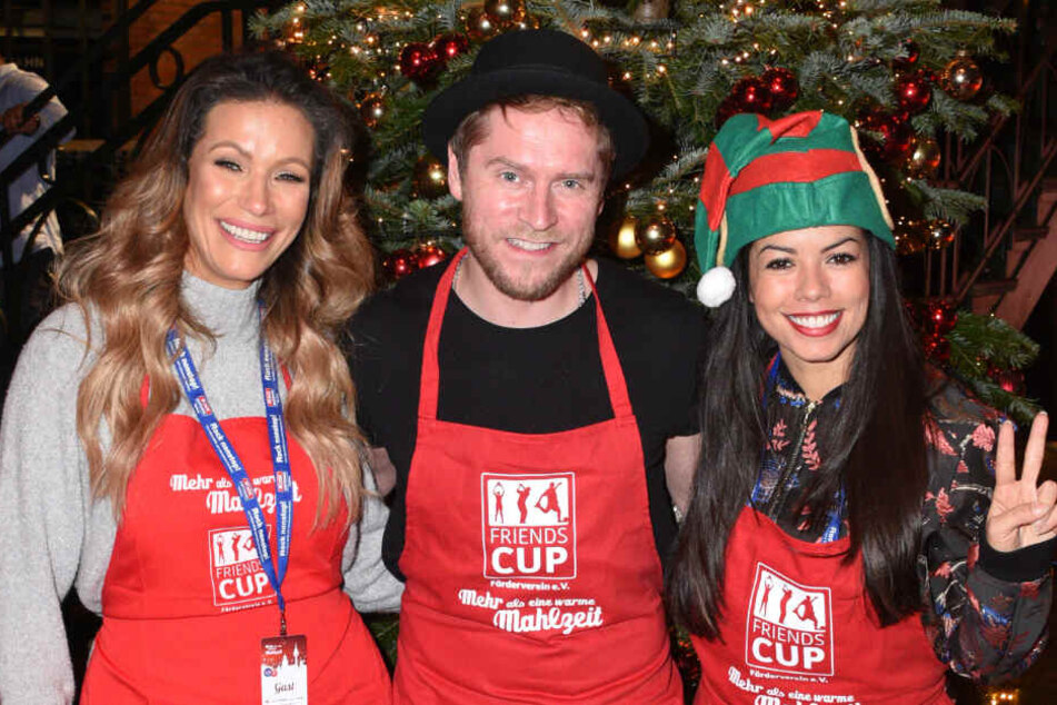 Yasmina Filali, Schauspielerin (l.), Johannes Oerding, Sänger und Fernanda Brandao (rechts), Sängerin, lächeln in der Fischauktionshalle bei der Weihnachtsfeier "Mehr als eine warme Mahlzeit".