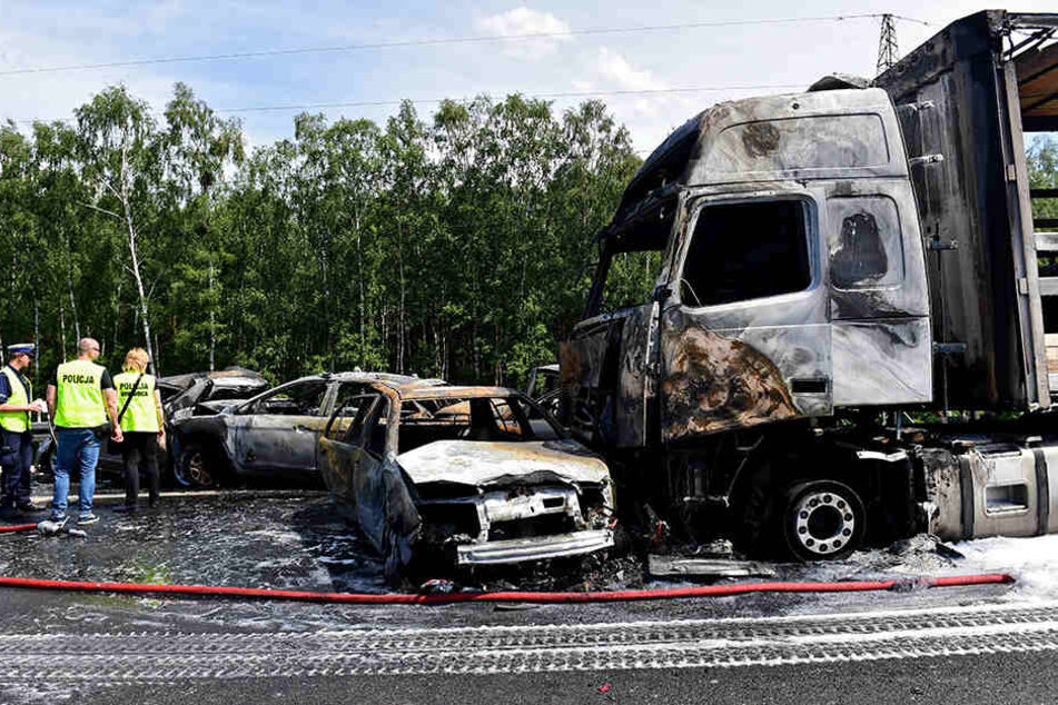 Polizisten stehen vor mehreren ausgebrannten Fahrzeugen auf der Autobahn A6 bei Stettin.