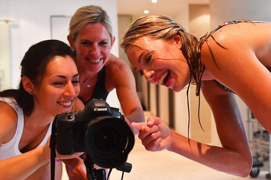 Fotografin Amelie Jehmlich, Beatrice Dömeland und Mittelblockerin Laura de Zwart (v.l.) schauen sich die gerade geschossenen Bilder an.