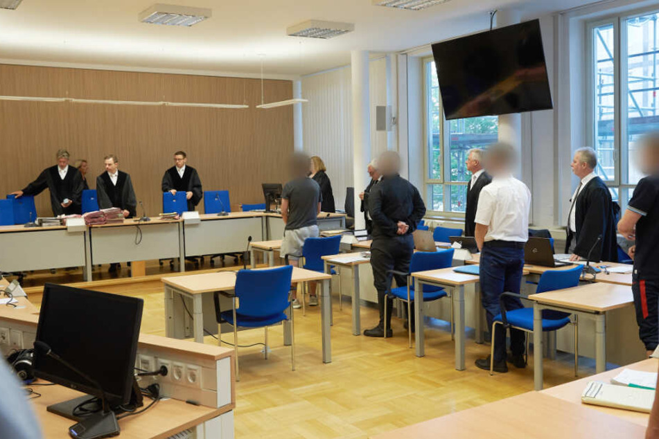 Die vier Angeklagten im Alter zwischen 18 und 24 Jahren stehen im Gerichtssaal des Landgerichts hinter den Anklagebänken.