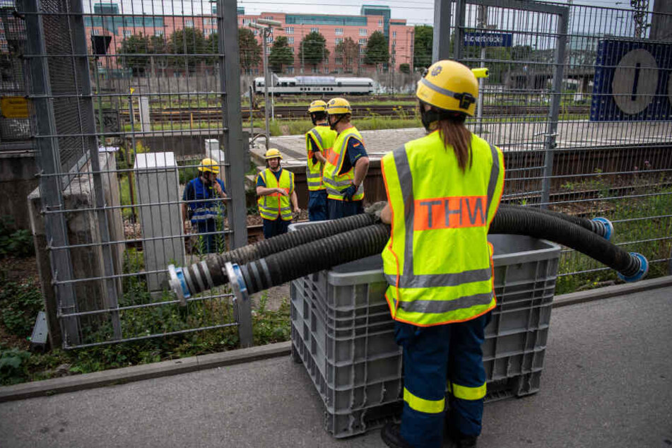 Einsatzkräfte des THW verlegen Schlauchleitungen auf den S-Bahngleisen.