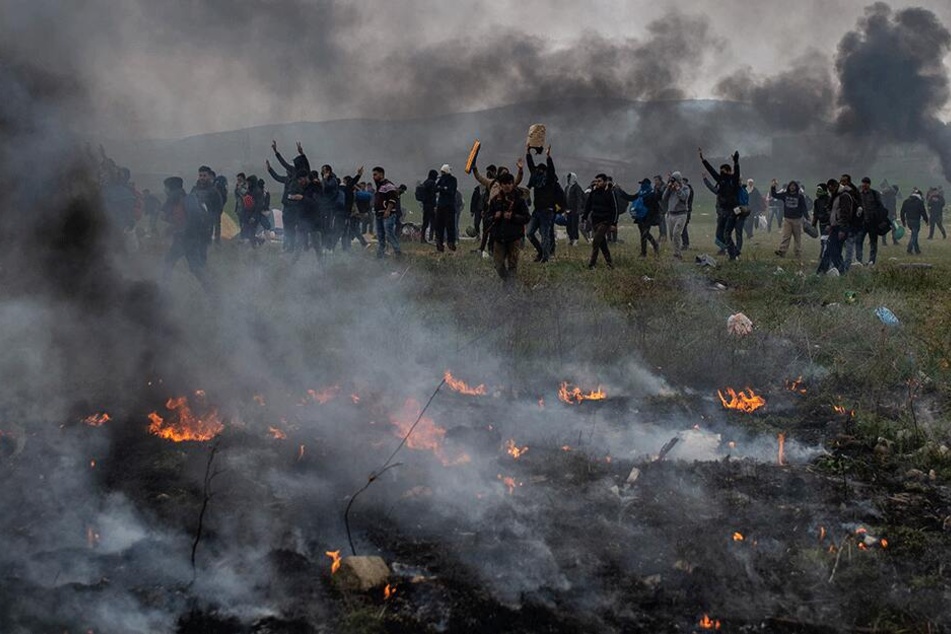 Protestierende Migranten stehen inmitten von Rauchwolken bei Zusammenstößen mit der Polizei nahe einem Flüchtlingslager im Dorf Diavata in der Nähe von Thessaloniki.