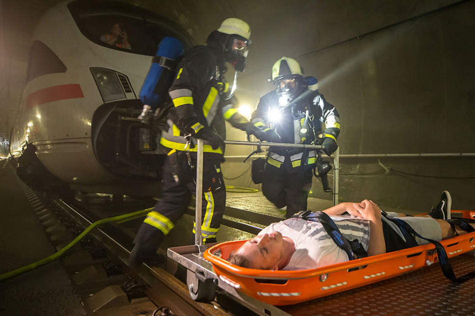 Feuerwehrmänner schieben einen "Verletzten" auf einem speziellen Schienenwagen aus dem Tunnel.