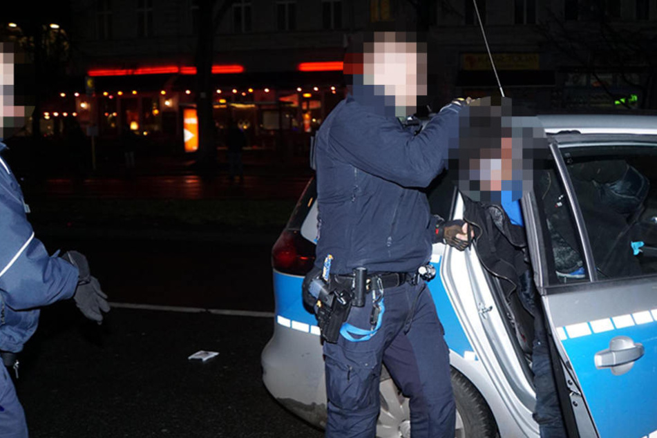 Die Polizei setzt einen der Verdächtigen ins Einsatzfahrzeug.
