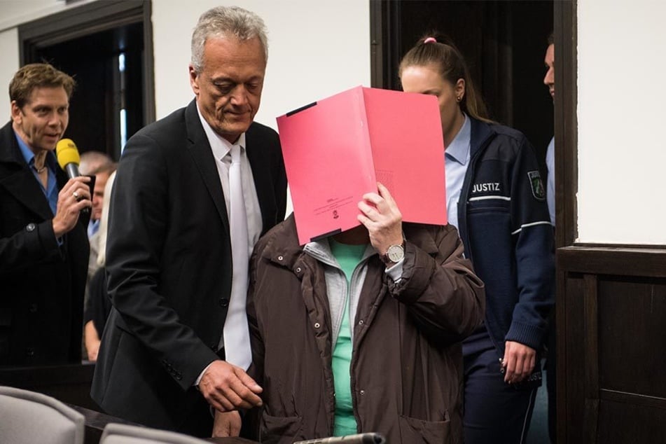 Angelika W. hielt sich bei Prozessbeginn eine rote Akte vor das Gesicht. Sie möchte nicht erkannt werden.