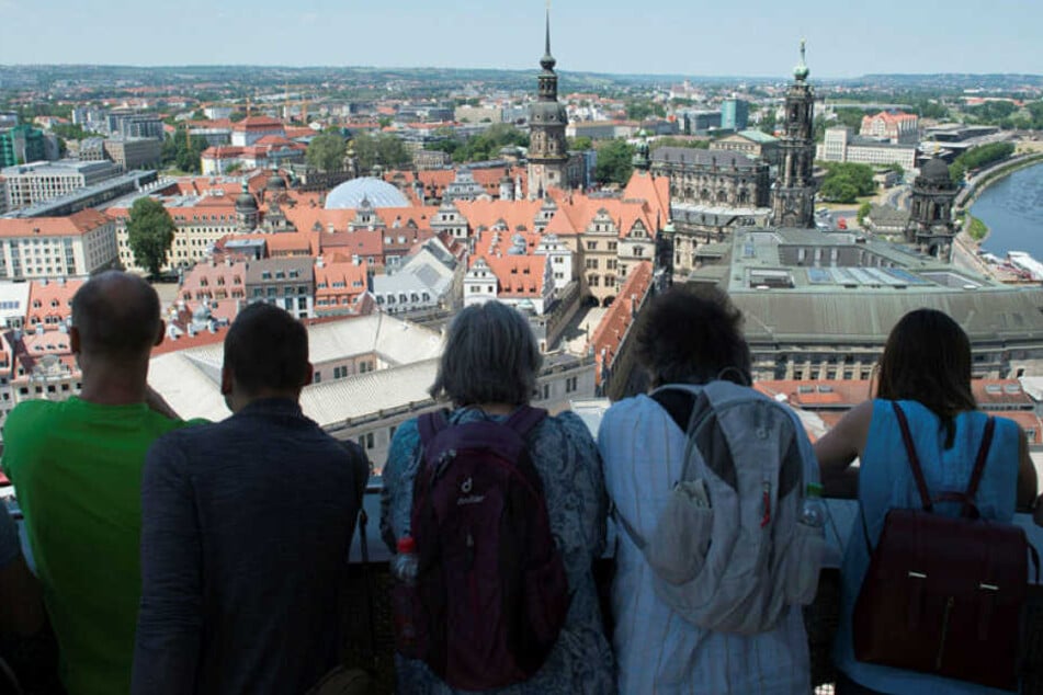 Touristen stehen auf der Kuppel der Dresdner Frauenkirche und blicken über die Altstadt.