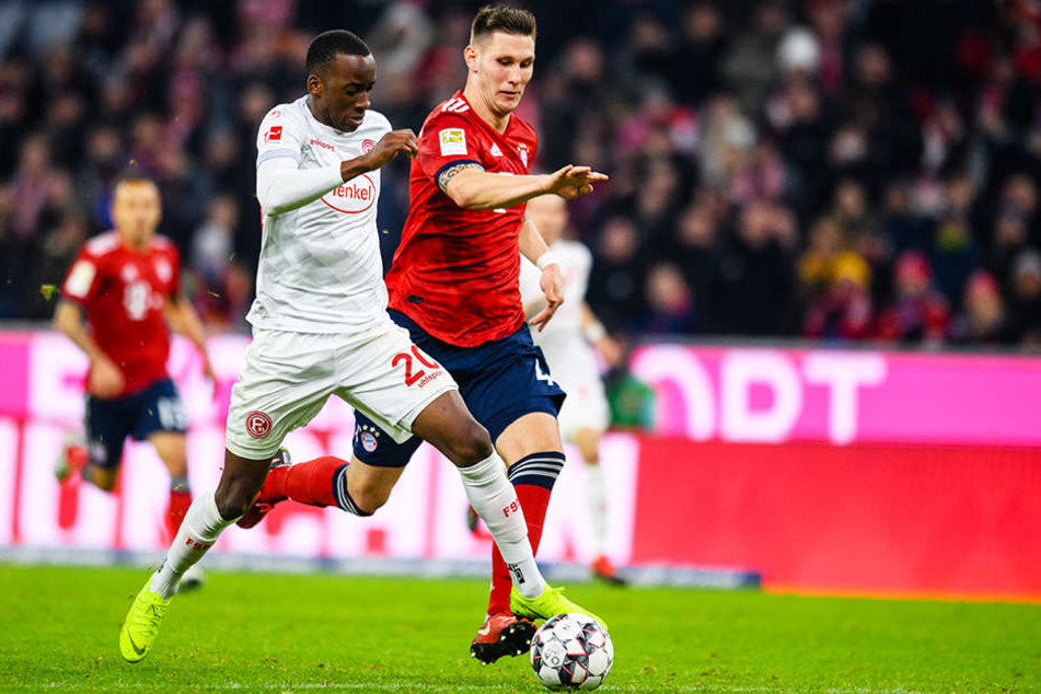 Düsseldorfs Dodi Lukebakio (l.) sprintet Bayerns Innenverteidiger Niklas Süle (r.) davon.