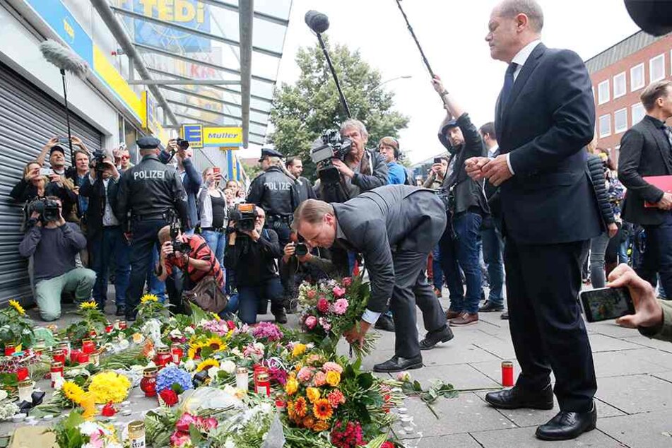 Blumen legt Hamburgs Innensenator Andy Grote (49, SPD) neben dem Ersten Bürgermeister Olaf Scholz (59, SPD, r) in Hamburg-Barmbek vor dem Supermarkt ab, in dem am 28. Juli ein Mann einen Menschen mit einem Messer getötet und sechs weitere verletzt hat.