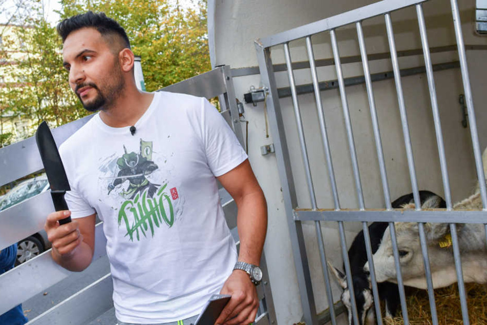 Der vegane Koch und TV-Promi Attila Hildmann steht in Berlin bei einem Pressetermin vor seinem veganen Imbiss mit einem Messer an einem Tiergatter.