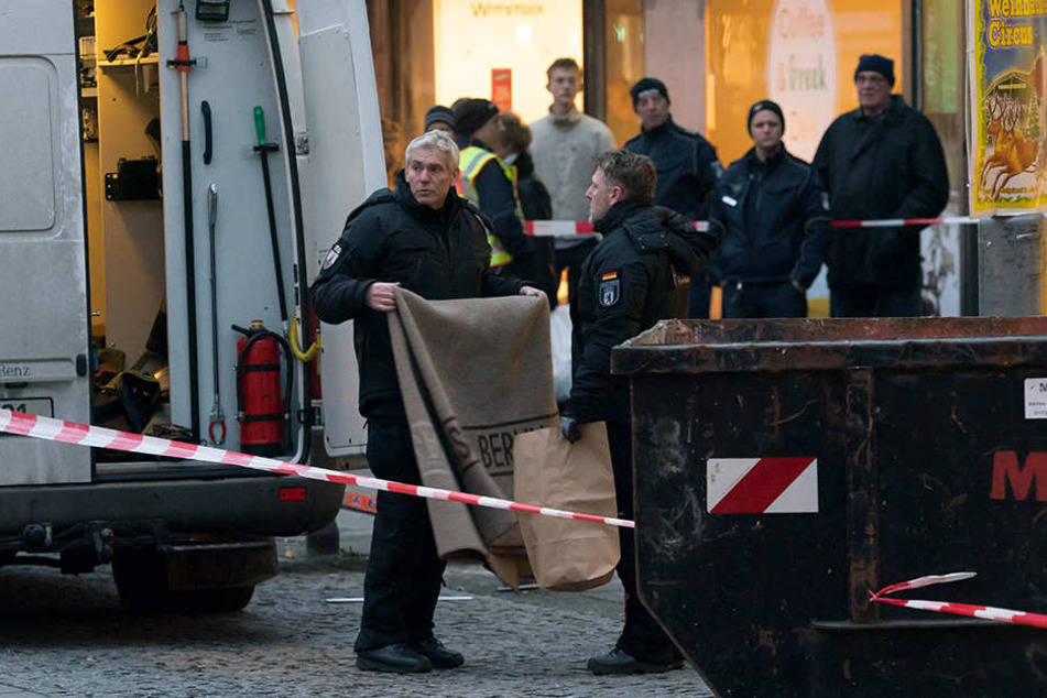 Polizisten bringen den Umschlag aus der Bank.