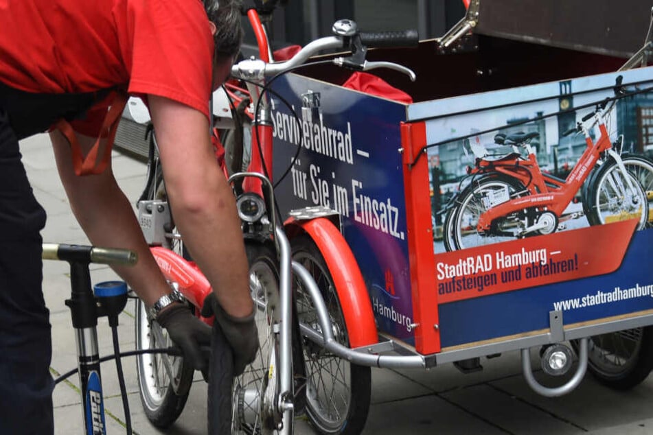 Ein Mitarbeiter kontrolliert die Reifen eines Stadtrads.