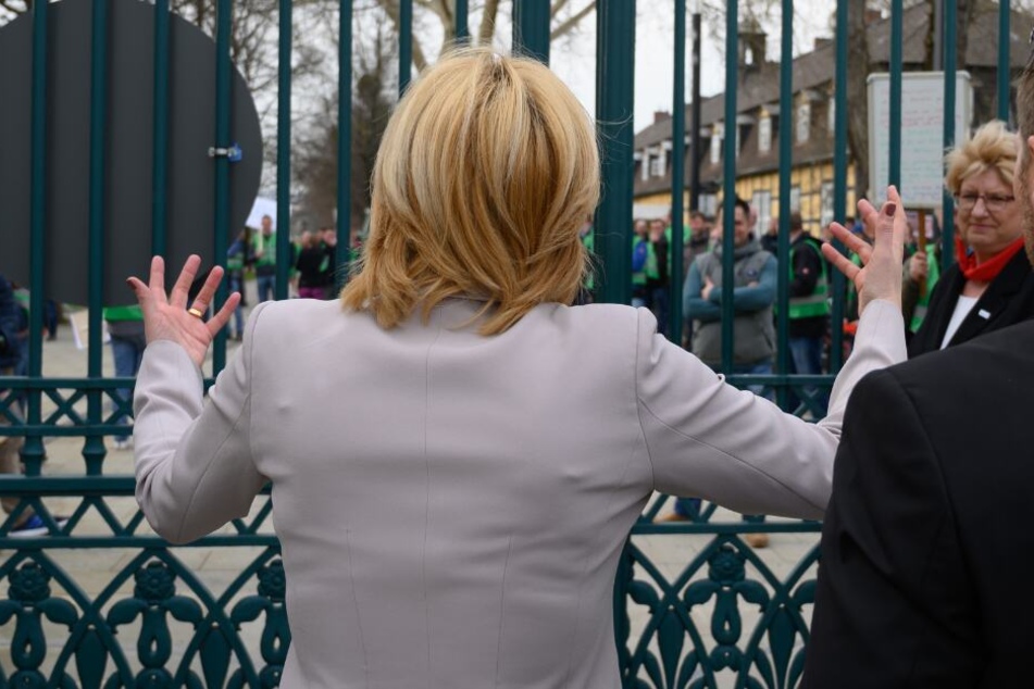 Julia Klöckner (CDU), Bundesministerin für Ernährung, Landwirtschaft und Verbraucherschutz geht auf Demonstranten zu, die hinter einem Gittertor stehen.