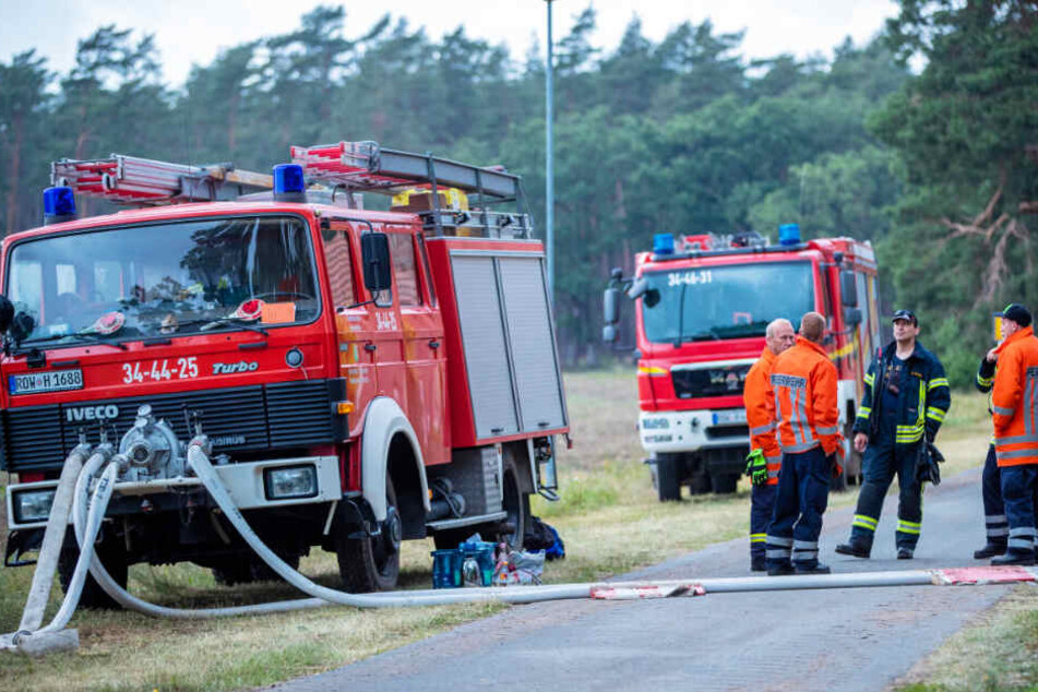 Feuerwehrleute warten bei Hohen Woos am Rand des brennenden Waldgebiet.