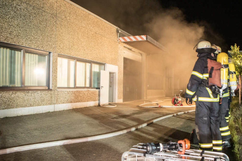 Einsatzkräfte beobachten den aus der Halle dringenden Rauch.