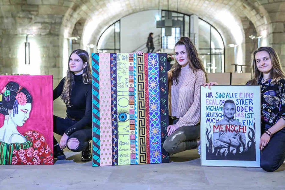 Die Gymnasiastinnen Larissa Witczak (17), Elisabeth Koch (17) und Anne Müller (18, v.l.) zeigen drei ihrer Bilder, die bis Montag in der Unterkirche der Frauenkirche zu sehen sind