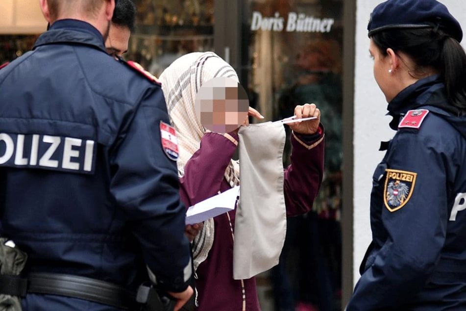 Polizisten kontrollieren eine verschleierte Frau in Österreich (Symbolbild).