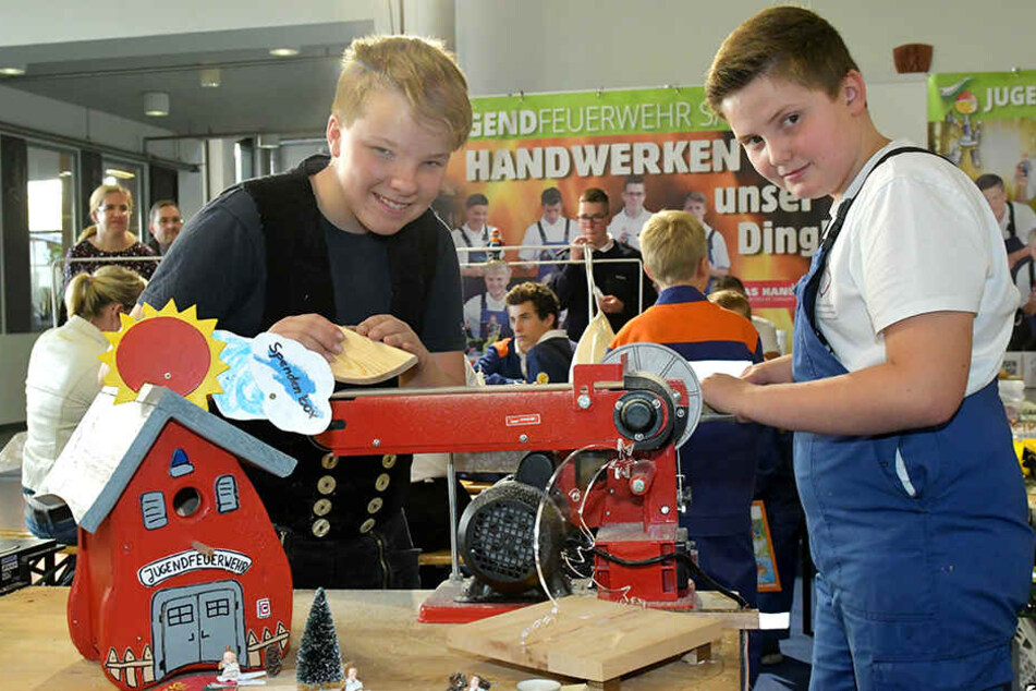 Nachwuchskräfte schulen ihr handwerkliches Geschick: Justin (12, l.) und Oskar (11) schleifen Holz am Stand der Jugendfeuerwehr Sachsen.