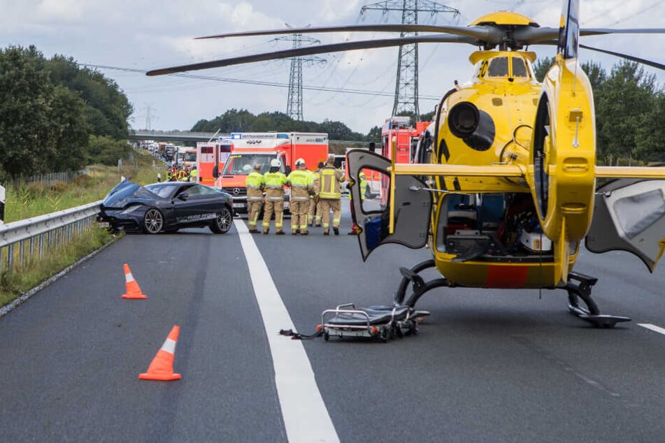 Ein Rettungshubschrauber steht auf der Autobahn. Ein Jaguar steht an der Leitplanke.