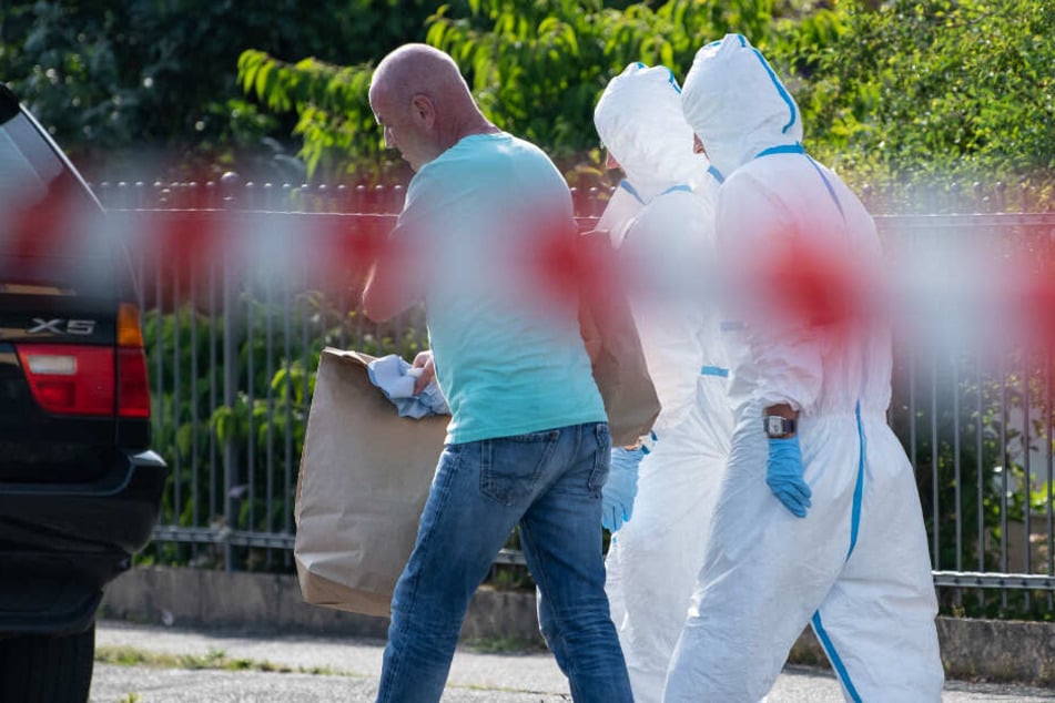 Mitarbeiter der Spurensicherung tragen Beweismaterial aus dem Einfamilienhaus.
