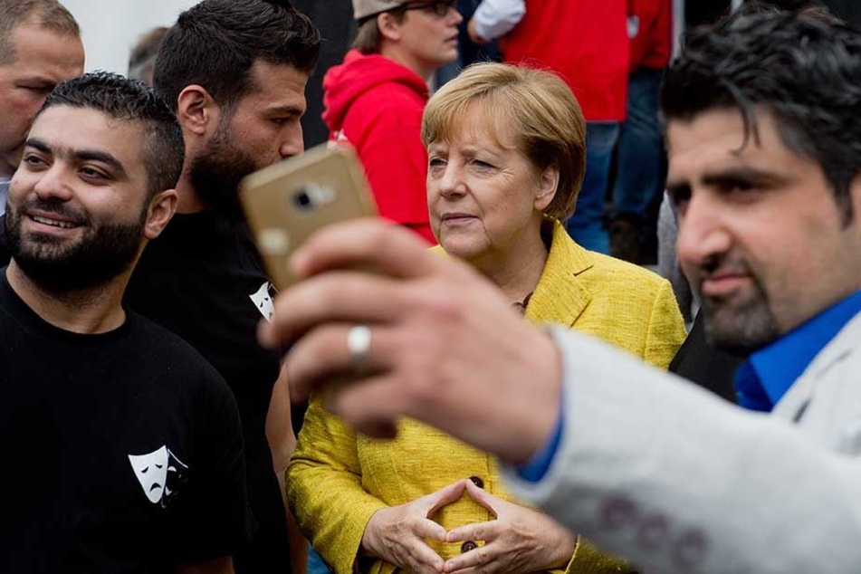 Angela Merkel wird 2015 von Flüchtlingen, die in Deutschland aufgenommen wurden, fotografiert.