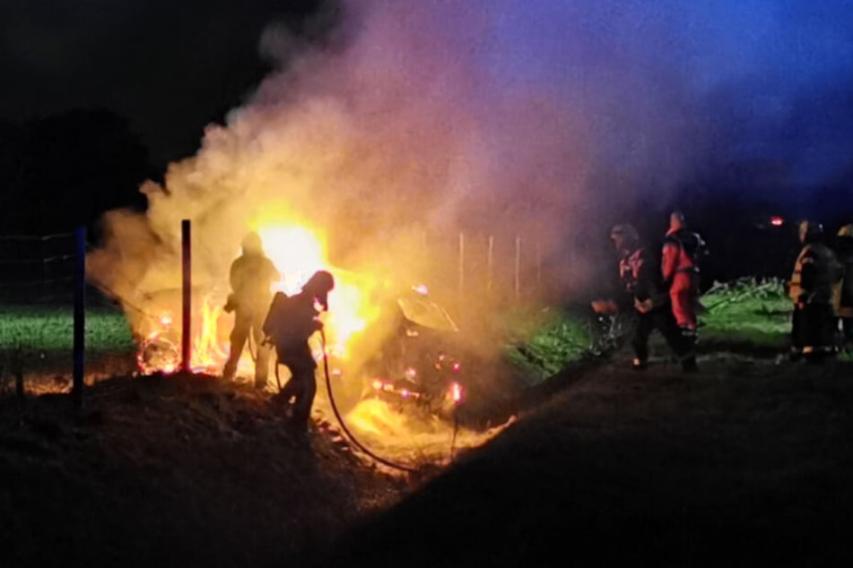 Die Feuerwehr löscht den brennenden SUV.