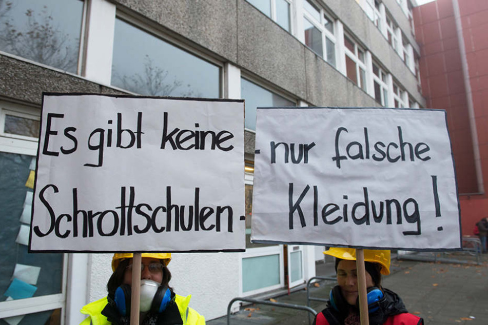 Zwei Demonstranten halten vor der Carlo-Schmid-Oberschule in Spandau Plakate in den Händen.