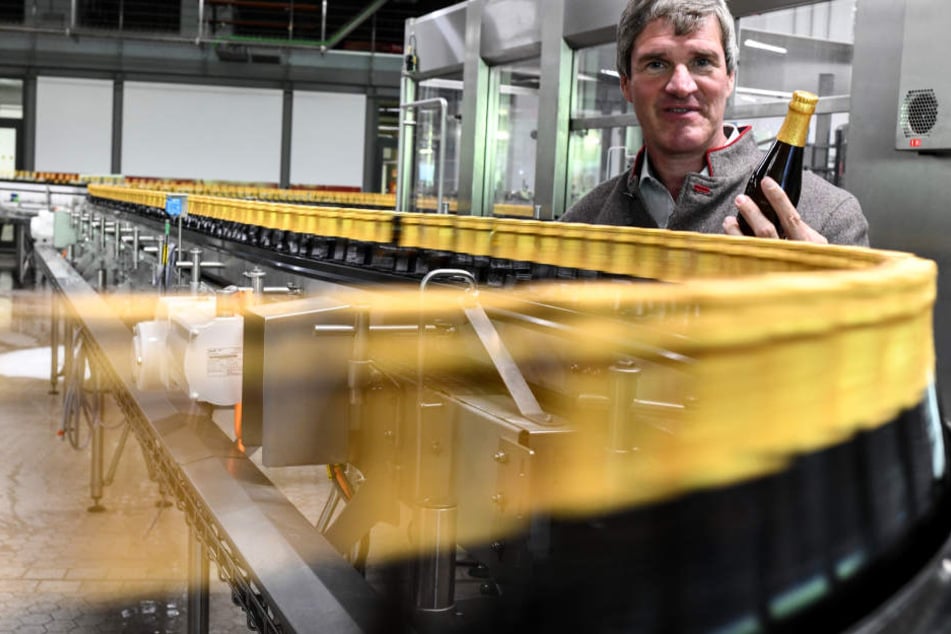 Vorstand Christian Rasch von der Badischen Staatsbrauerei Rothaus steht in der Abfüllanlage und hat einer Flasche "Tannenzäpfle" in der Hand.