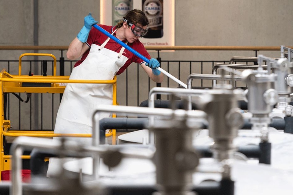 Ein Brauergeselle reinigt in einer Brauerei die Lagertanks.