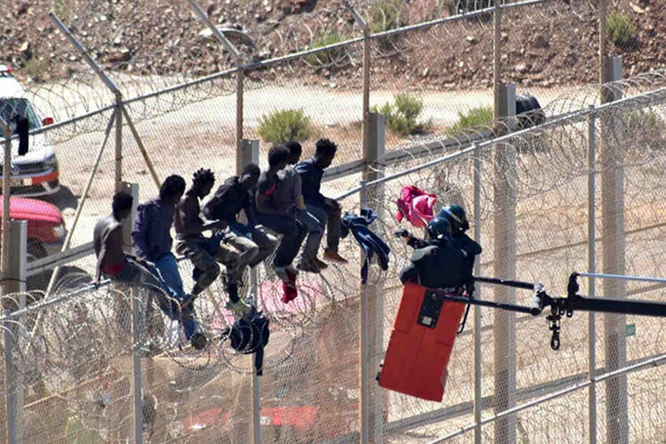 Flüchtlinge sitzen im September 2016 auf dem Grenzzaun, der die spanische Enklave Ceuta von Marokko trennt.