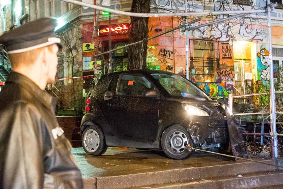 Ein Polizist schaut sich den demolierten Wagen an, der die Treppe herunter raste.