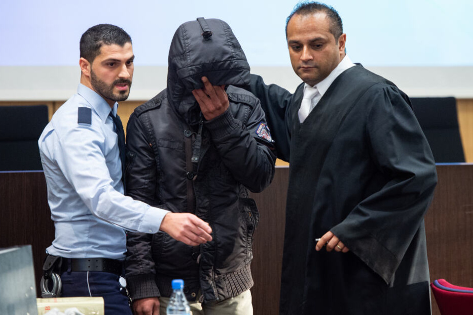 Der angeklagte Familienvater wird von einem Justizbeamten und einem seiner Verteidiger, in einen Saal im Land- und Amtsgericht Düsseldorf geführt.