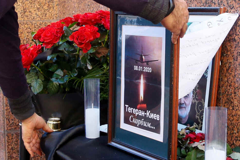 Ein Mann platziert ein Gedenkplakat mit der Aufschrift "Teheran - Kiew, wir trauern".