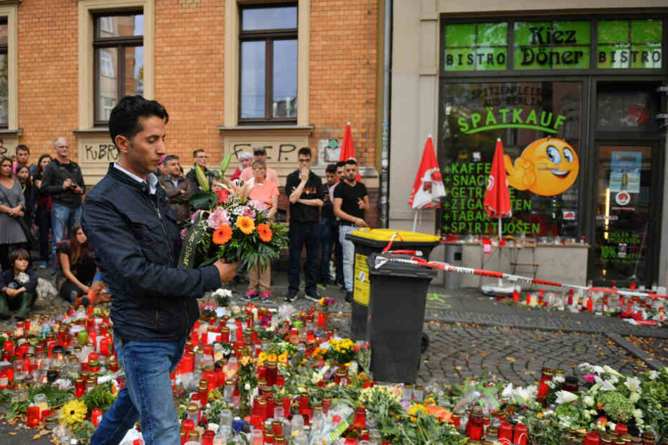 Ein Mitarbeiter des Kiez Döners legt Blumen am Gedenkort vor dem Imbiss ab.