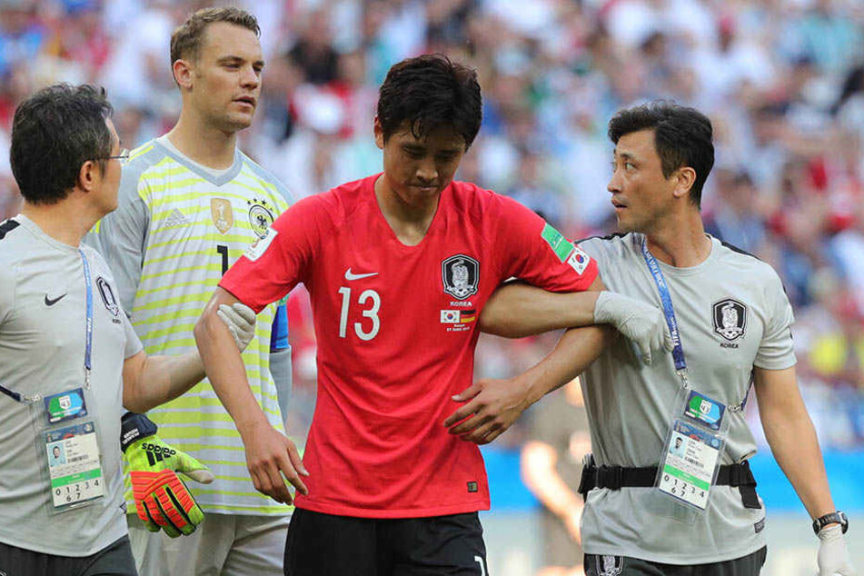 Ja-Cheol Koo (29, Mitte) musste verletzt behandelt werden. Im Hintergrund der deutsche Torhüter Manuel Neuer (32).