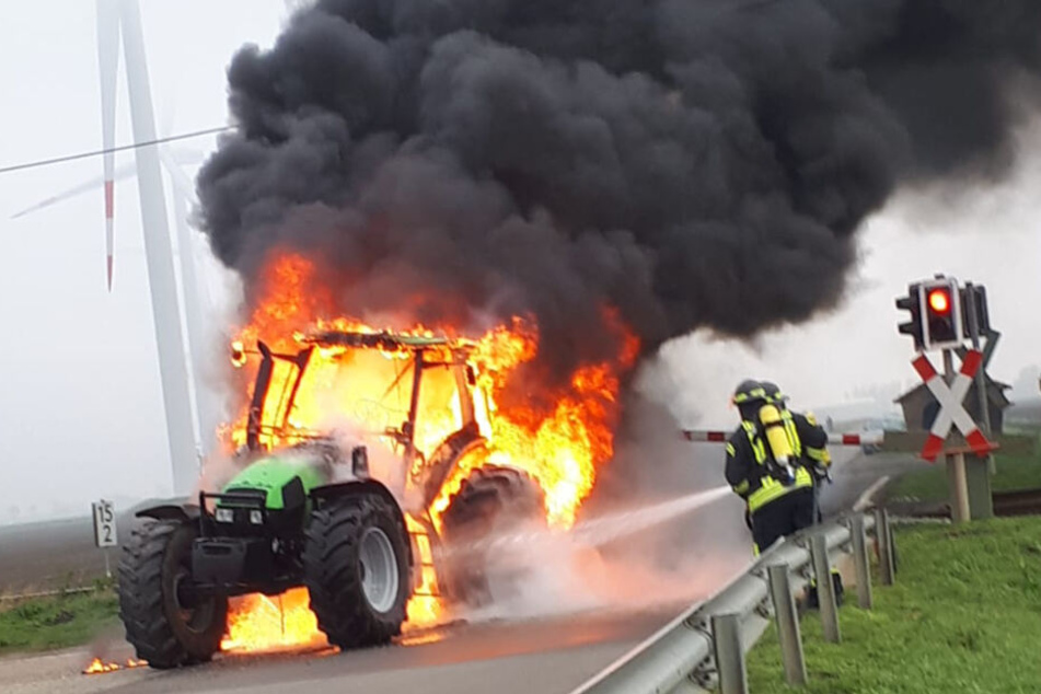 Die Feuerwehr löscht den lichterloh brennenden Traktor an den Bahngleisen.