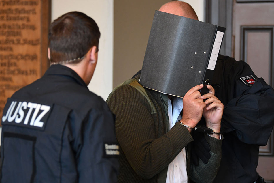 Der 32-jährige Angeklagte Kaire M. verdeckte bei Prozessbeginn sein Gesicht mit einem Aktenordner.