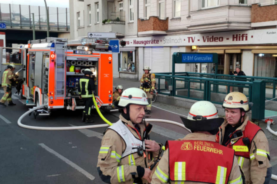 Berliner Feuerwehrmänner beraten sich vorm Eingang zum U-Bahnhof Grenzallee.