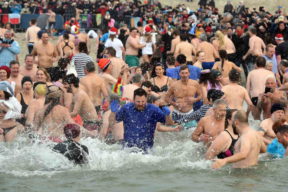 Wetterfeste Winterbader stürzen sich in das kalte Wasser am Strand.