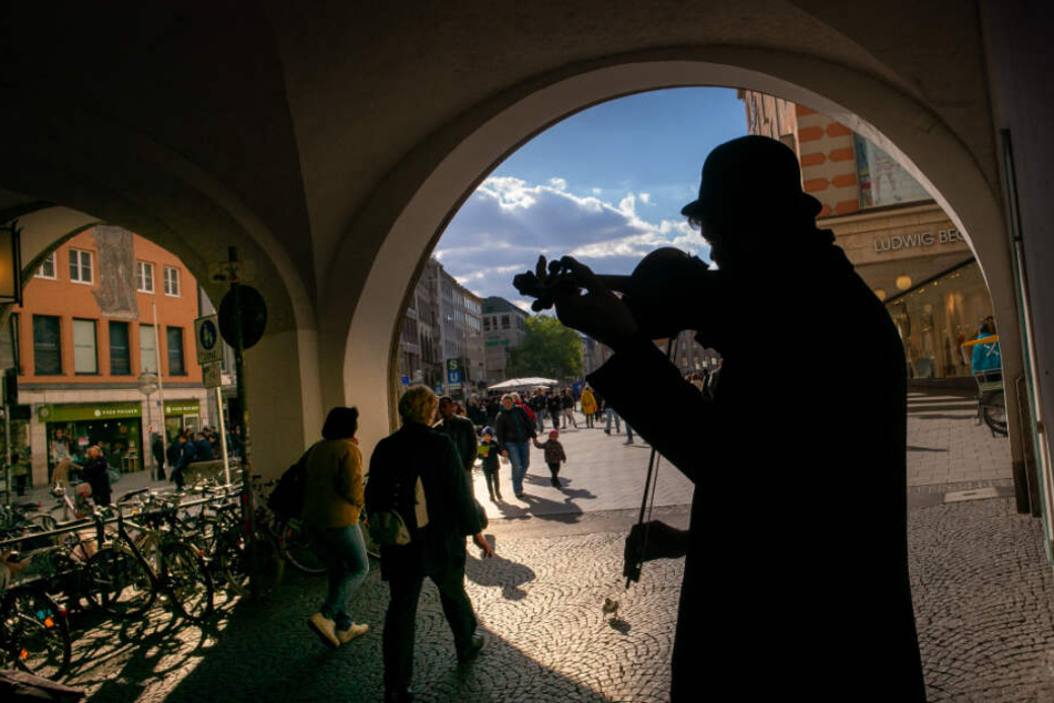 Ein Straßenmusiker spielt in der Fußgängerzone in der Münchner Innenstadt auf seiner Geige.